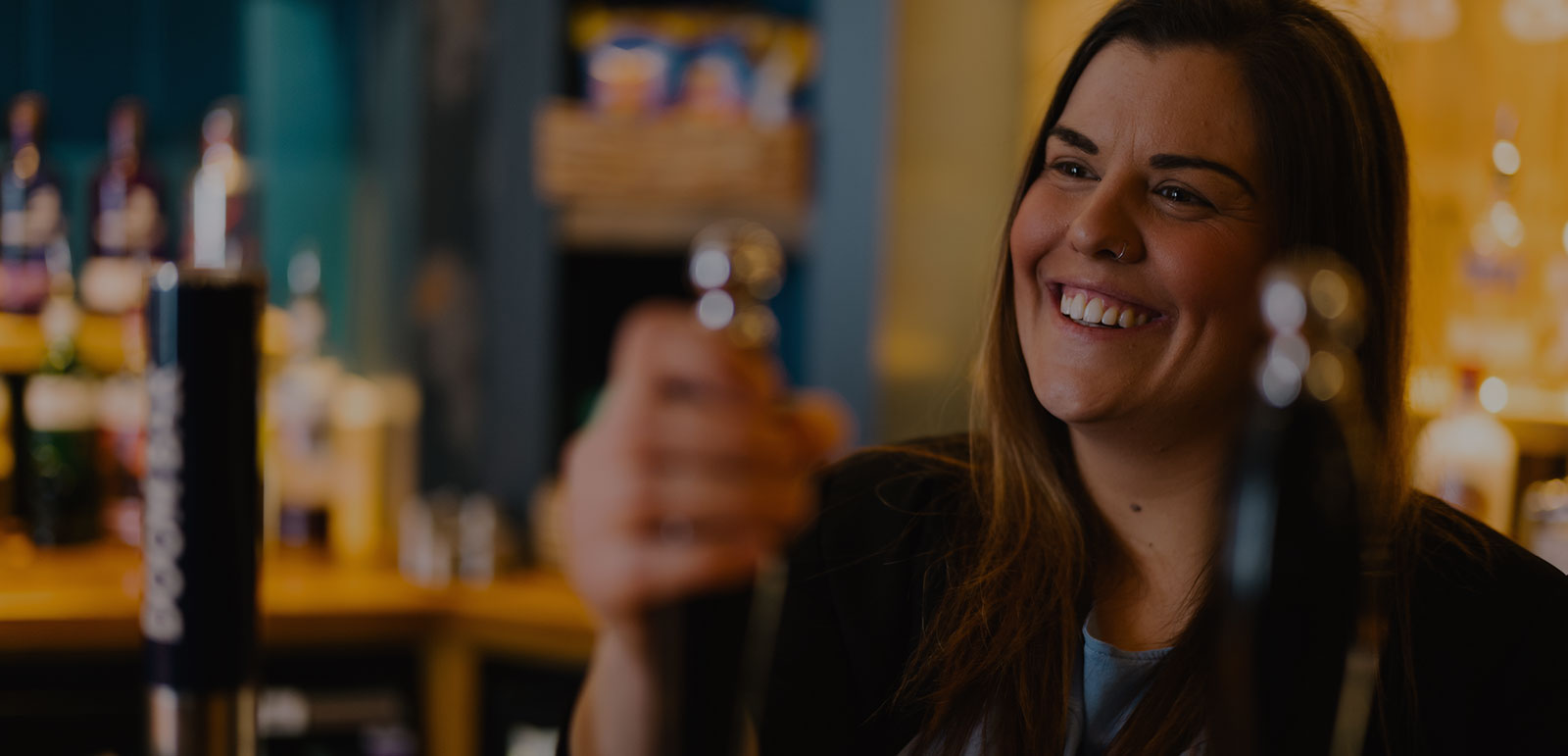 smiling bar staff pulling a pint